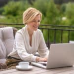 Joyful woman writing an email on the notebook computer