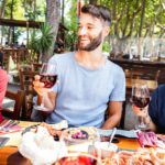 Millenial people having fun drinking red wine glasses at lunch party on sunny day