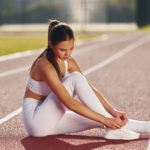 On the ground. Young woman in sportive clothes is exercising outdoors