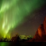 View of aurora borealis over sea and snow capped mountains, Reine, Norway